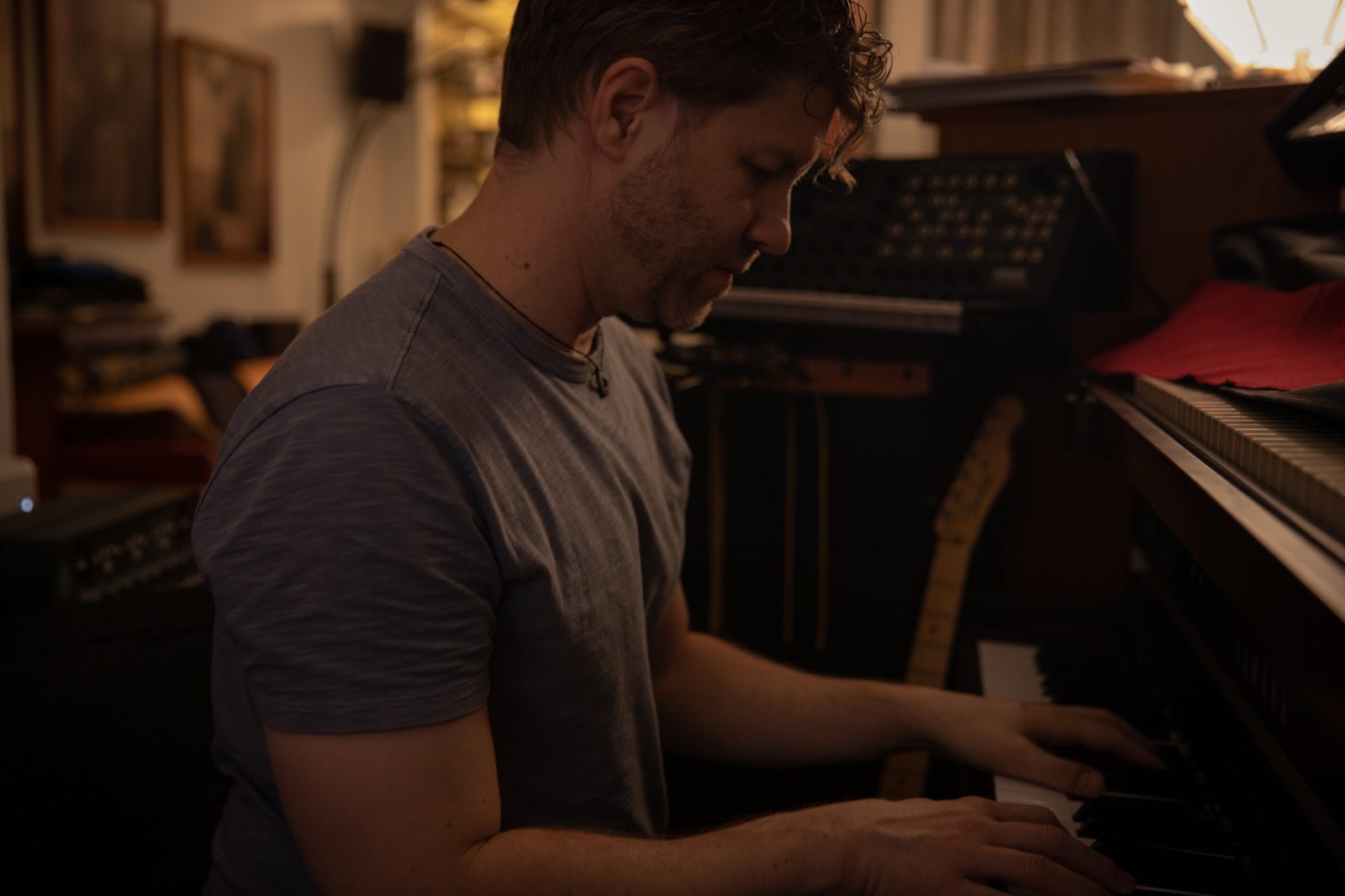 Thomas at the piano in his studio, synthesizers behind him